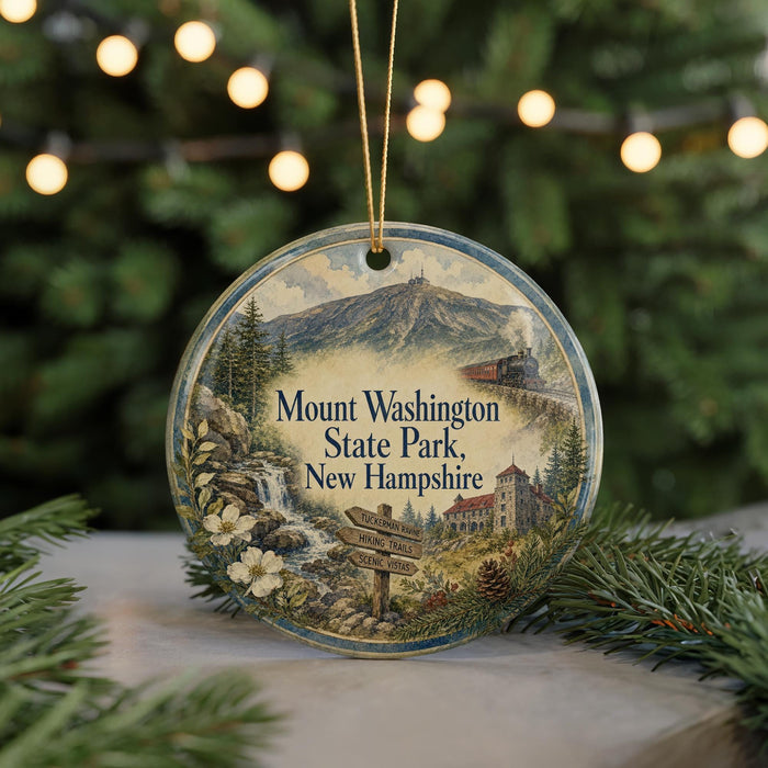 A round ornament with a scenic mountain landscape and a train, hanging on a string.