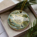 A decorative ornament in a box, featuring a scenic image of Moutail Landing State Park in Tennessee.