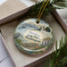 A decorative ornament in a box, featuring a scenic image of Mukilteo State Park in Washington.