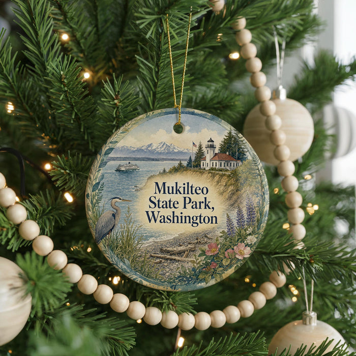 A round ornament hanging on a Christmas tree, featuring a scenic image of Mukilteo State Park in Washington.