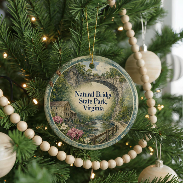 A round ornament hanging on a Christmas tree, featuring a scenic image of the Natural Bridge State Park in Virginia.
