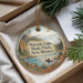 A decorative ornament with a scenic image of a lake and mountains, featuring a person in a boat, is displayed in a box with pine branches.