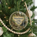 A round ornament hanging on a Christmas tree, featuring a scenic landscape with a waterfall and trees.