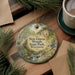 A decorative ornament featuring a scenic landscape of New Glarus Woods State Park, Wisconsin, with a bird perched on a branch and a stream flowing through the forest.