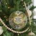 A round ornament hanging on a Christmas tree, featuring a scenic landscape with a river, waterfall, and a bird in flight.