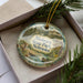 A decorative ornament in a box, featuring a scenic landscape of Niobrara State Park, Nebraska.