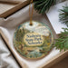 A decorative ornament with a landscape scene featuring a river, mountains, and a goat, hanging from a string.