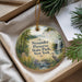 A decorative ornament with a scenic landscape of a forest, a waterfall, and a bird, placed in a box with pine branches.