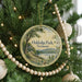 A round ornament on a Christmas tree, featuring a scenic landscape of Oakledge Park, Vermont.