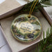 A decorative ornament in a box, featuring a scenic image of Pennsylvania State Park with a train and a waterfall.