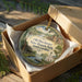 A decorative ornament in a wooden box, featuring a scenic landscape with buildings and greenery, with the text "Old Dorchester State Historic Park, South Carolina" printed on it.