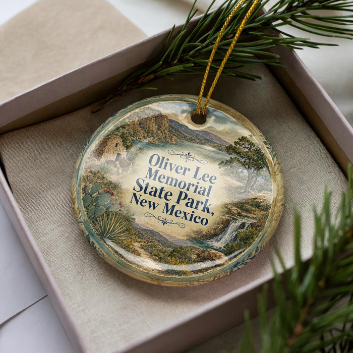 A decorative ornament in a box, featuring a landscape scene with mountains, trees, and a river.