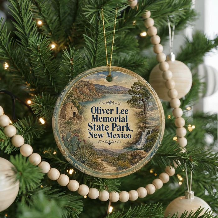 A round ornament hanging on a Christmas tree, featuring a scenic landscape with a waterfall and mountains.