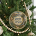 A round ornament hanging on a Christmas tree, featuring a scenic landscape with a waterfall and mountains.