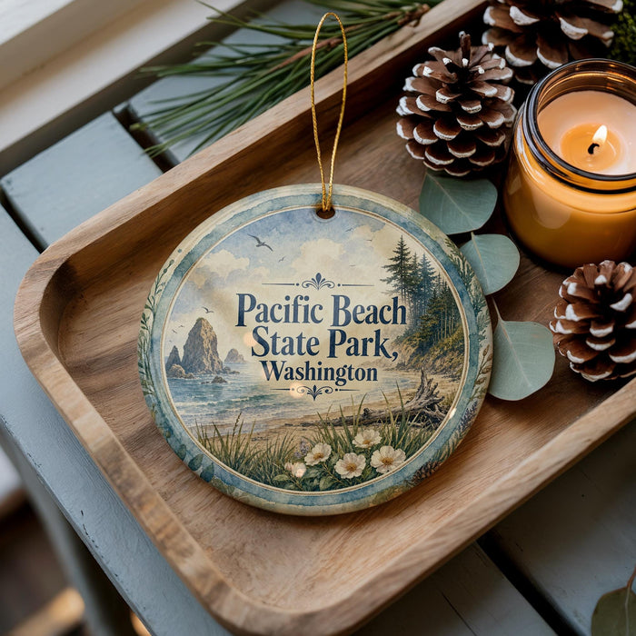 A decorative ornament with a scenic image of Pacific Beach State Park in Washington, accompanied by pine cones and a lit candle on a wooden tray.