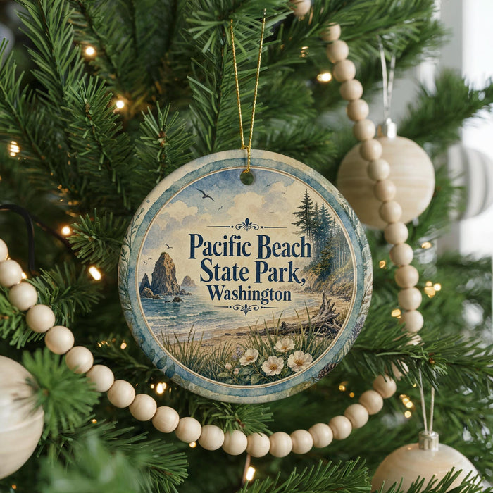 A round ornament hanging on a Christmas tree, featuring a scenic image of Pacific Beach State Park in Washington.