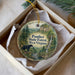 A decorative ornament in a box, featuring a scenic image of the Panther State Forest in West Virginia.