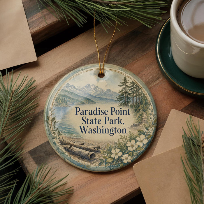 A decorative ornament with a scenic landscape of mountains, pine trees, and a lake, hanging on a wooden surface.