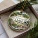 A decorative ornament in a box, featuring a scenic image of Paterson State Park in Pennsylvania.