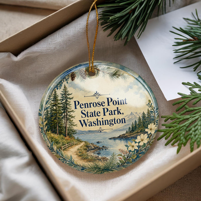 A decorative ornament with a scenic landscape of Penrose Point State Park, Washington, featuring pine trees, a river, and mountains.