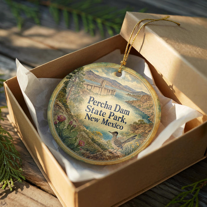 A decorative ornament in a box, featuring a scenic landscape with a bird and a bridge.