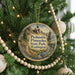 A round ornament hanging on a Christmas tree, featuring a scenic landscape with mountains and a river.