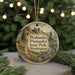 A circular ornament with a scenic mountain landscape and text, hanging on a string.