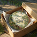 A decorative ornament in a wooden box, featuring a scenic landscape with a lake, trees, and a canoe, along with the text "Pike Lake State Park, Ohio".
