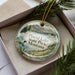 A decorative ornament in a box, featuring a scenic landscape of Placid Lake, State Park, Montana.