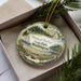 A decorative ornament with a scenic image of Pleasant Harbor State Park in Washington, featuring a lighthouse and a river.