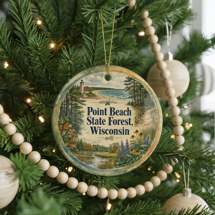 A round ornament hanging on a Christmas tree, featuring a scenic landscape with a lighthouse and a beach.
