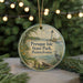 A round ornament with a lighthouse and a scenic view of Presque Isle State Park, Pennsylvania, hanging from a string.