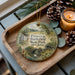A decorative ornament featuring a scenic image of Princeton Battlefield State Park, New Jersey, with a candle and pine cones on a wooden tray.