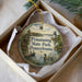 A decorative ornament in a box, featuring a scenic image of a lake, a lighthouse, and a duck.