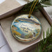 A decorative ornament featuring a scenic image of Quail Creek State Park in Utah, with a bird perched on a rock in the foreground.