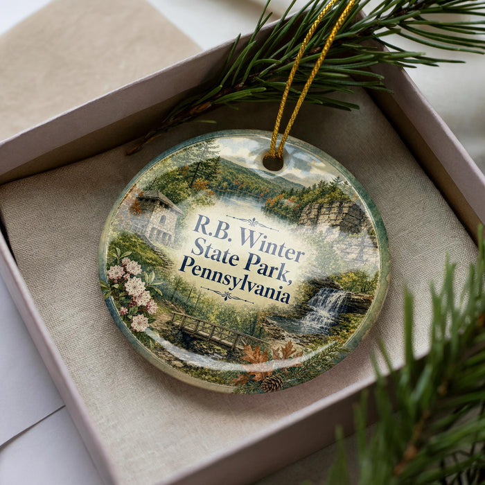 A decorative ornament in a box, featuring a scenic image of Pennsylvania State Park with a waterfall and pine trees.