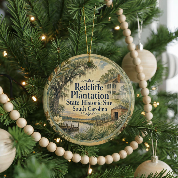 A round ornament hanging on a Christmas tree, featuring a scenic image of a historic plantation in South Carolina.
