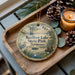 A wooden tray with a decorative ornament featuring a serene landscape of Reelfoot Lake, Tennessee, and pine cones.