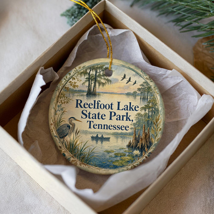 A decorative ornament in a box, featuring a scenic image of Reelfoot Lake State Park in Tennessee.