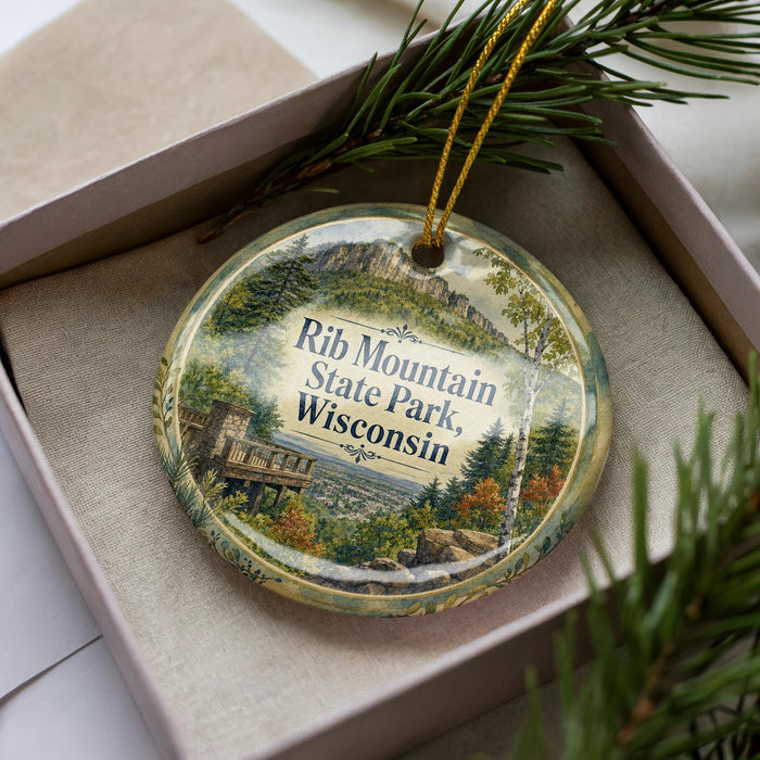 A decorative ornament in a box, featuring a scenic image of Rib Mountain State Park in Wisconsin.