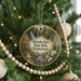 A round ornament hanging on a Christmas tree, featuring a scenic image of a waterfall surrounded by trees and a path.