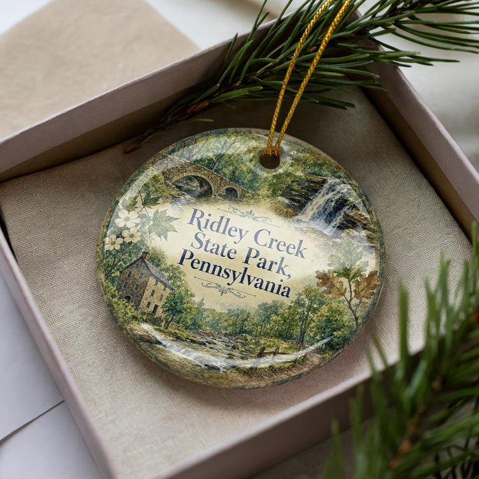 A decorative ornament in a box, featuring a scenic image of Ridley Creek State Park in Pennsylvania.