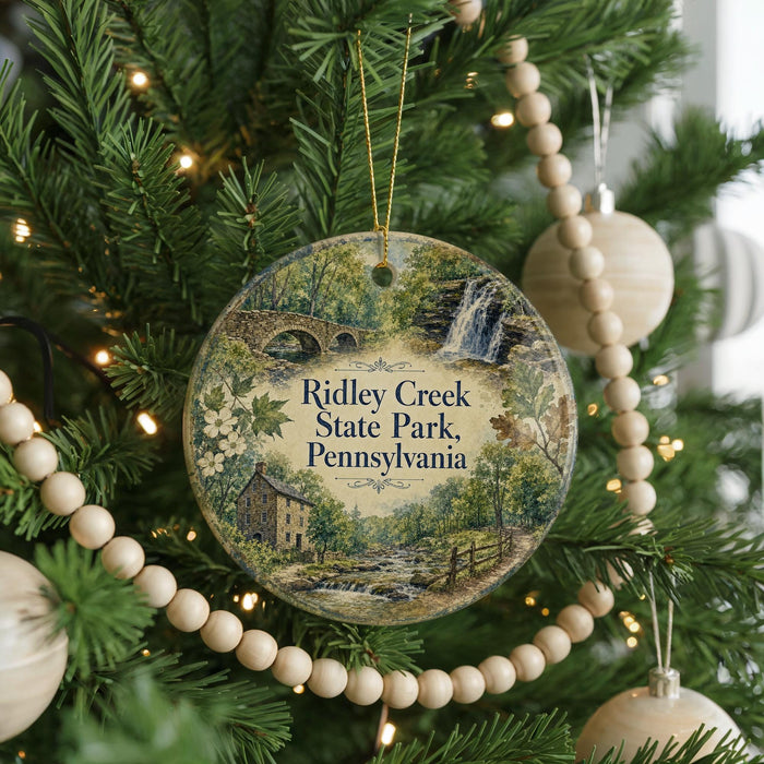A round ornament hanging on a Christmas tree, featuring a scenic image of Ridley Creek State Park in Pennsylvania.