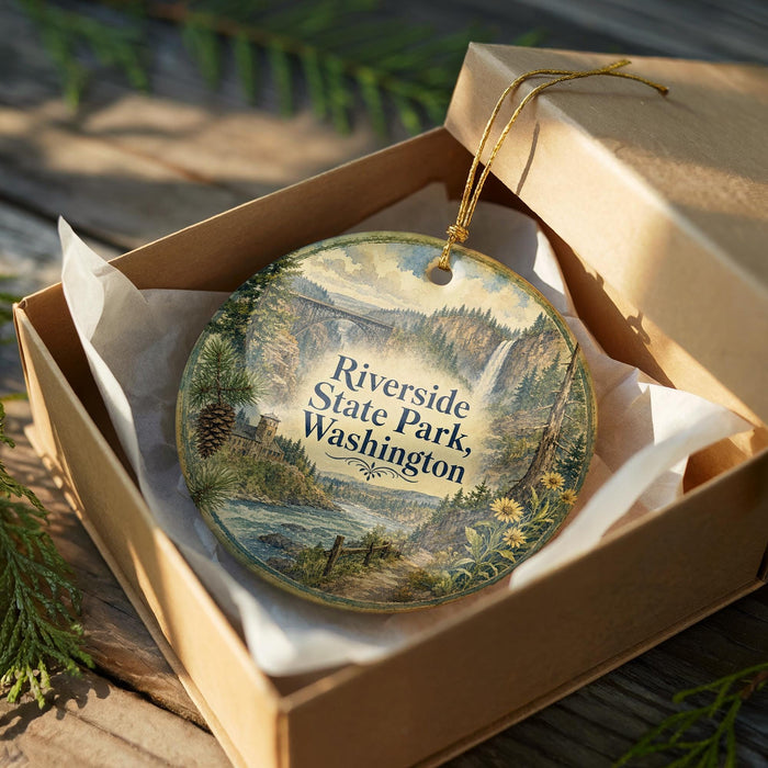 A decorative ornament in a wooden box, featuring a scenic landscape with a river, mountains, and pine trees.