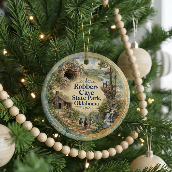 A Christmas tree ornament featuring a scenic image of Robbers Cave State Park in Oklahoma, with a small cabin and a path leading to a waterfall.