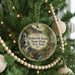 A round ornament hanging on a Christmas tree, featuring a scenic image of Robert H. Treman State Park in New York.