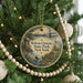 A round ornament hanging on a Christmas tree, featuring a scenic image of Roberto Clemente State Park in New York.