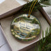 A decorative ornament with a scenic image of Rock Island State Park, Tennessee, displayed in a box with pine branches.