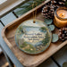 A wooden tray with a decorative ornament featuring a scenic landscape of Round Valley Recreation Area in New Jersey, accompanied by pine cones and a lit candle.