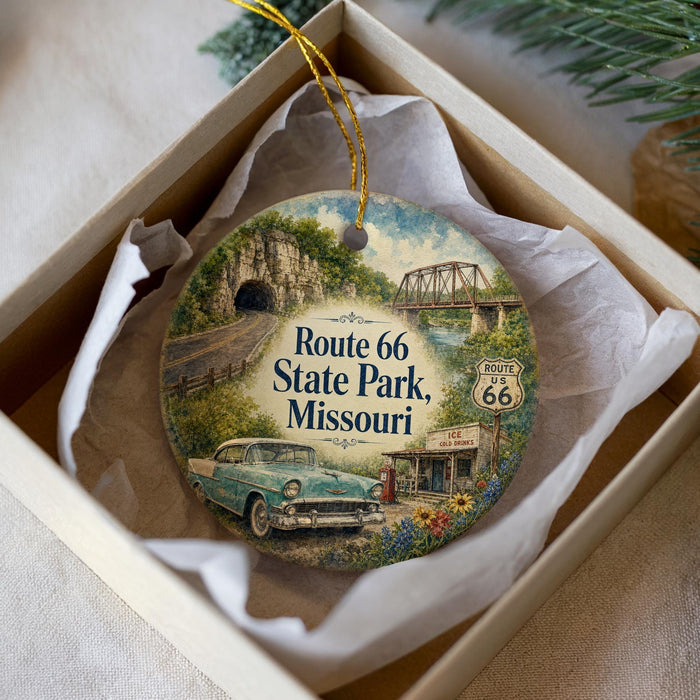 A decorative ornament in a white box, featuring a vintage car and a scenic landscape with Route 66 and Route 66 State Park in Missouri.